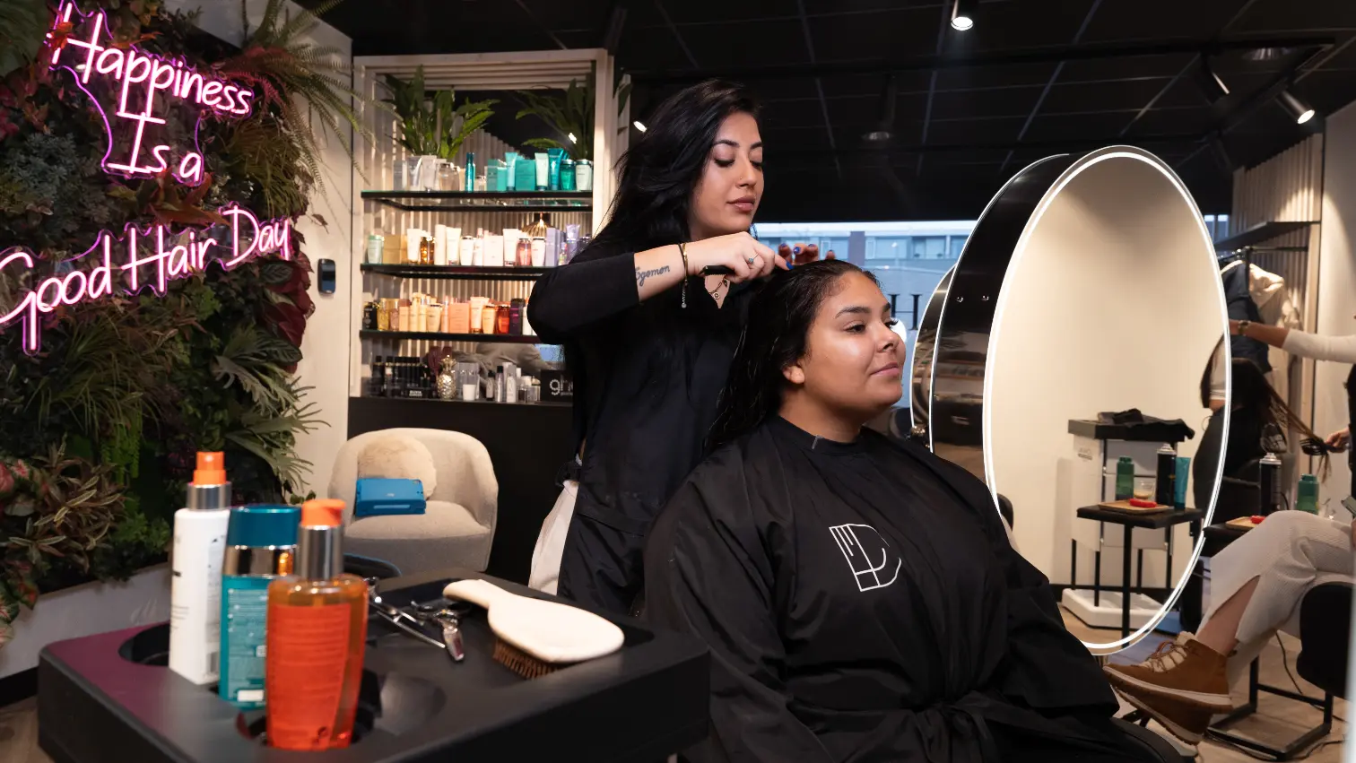 Beschrijving: Twee vrouwen die hun haar laten knippen in een salon.