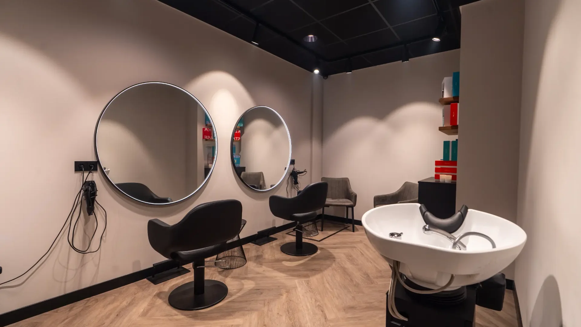Een kapsalon met spiegels, stoelen en een hoofddoekgedeelte.